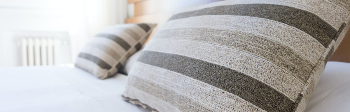 Gray and black throw pillow on bed.