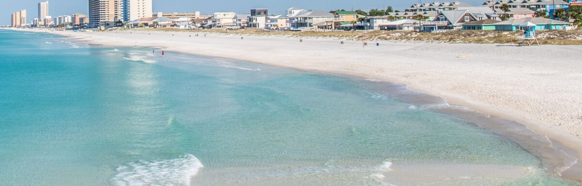 Panama City Beach with building and houses in the background during the day.