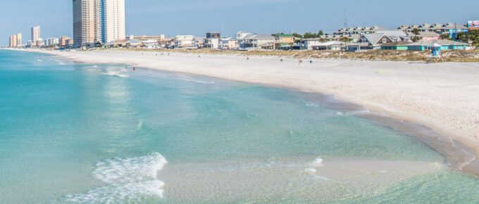 Panama City Beach with building and houses in the background during the day.