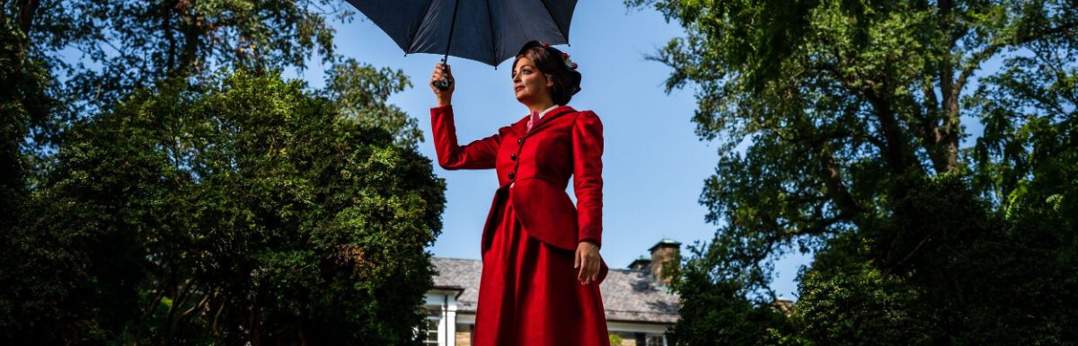 Marry Poppins, wearing a red dress and holding a black umbrella.