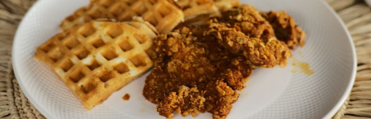 Chicken and waffles on a white plate.