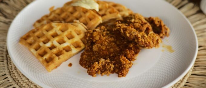 Chicken and waffles on a white plate.