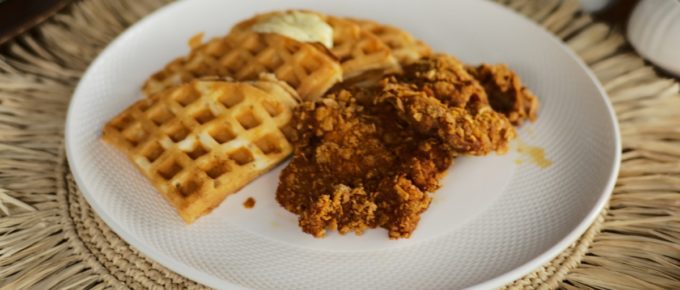 Delicious chicken and waffles on a white plate.