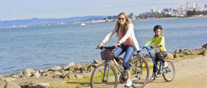 Mother and Daughter biking along the beach in California, USA.