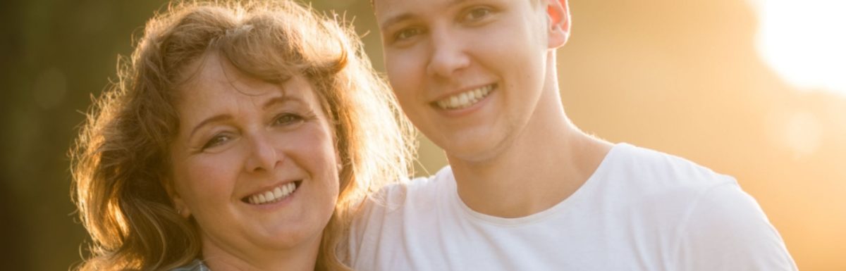 Mother with her adult son side hugging.