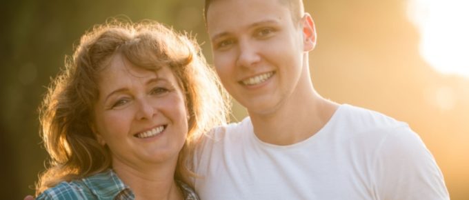 Mother with her adult son side hugging.