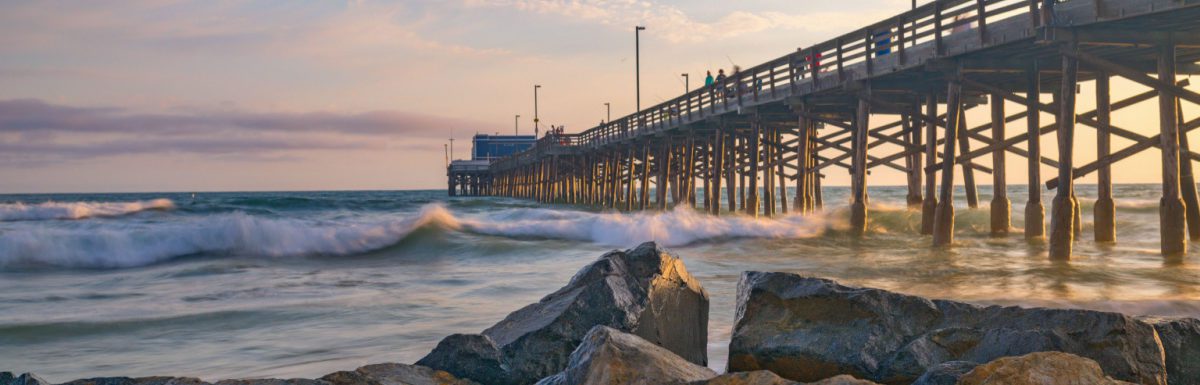 Beautiful golden hour with colorful scattered clouds as the sun sets over Balboa Pier on Newport Beach in California USA near Anaheim.