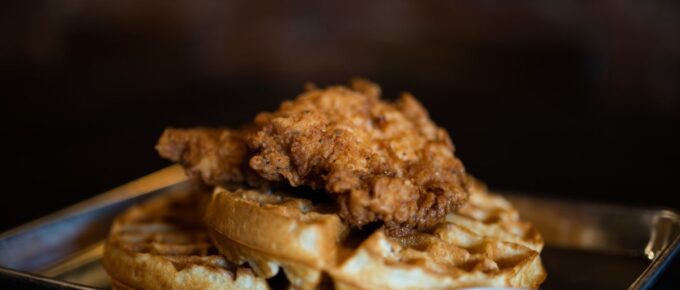 Waffle with fried chicken on top on a plate.