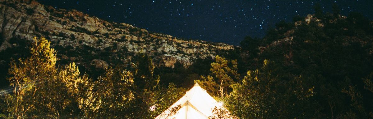 A lit up tent at night in the mountains.