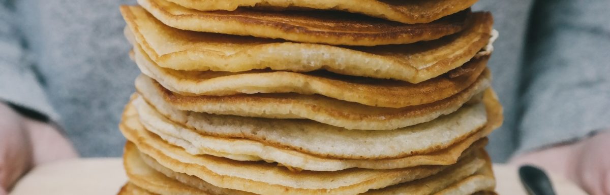 A pile of delicious pancakes on a chopping board for breakfast in bed.