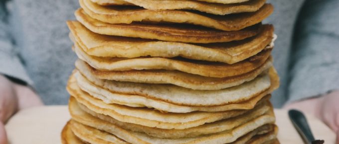 A pile of delicious pancakes on a chopping board for breakfast in bed.
