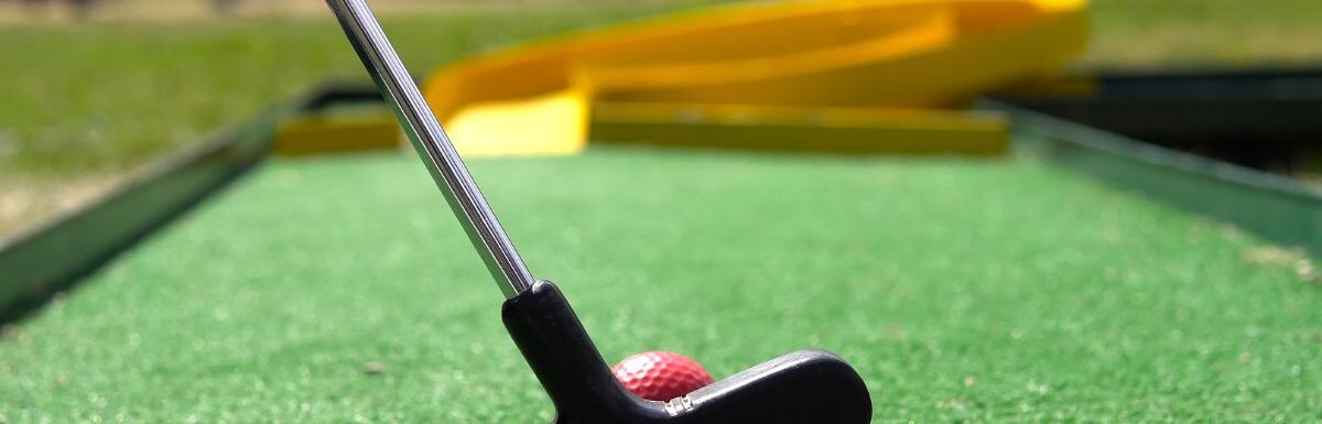 Closeup of player play mini golf with red ball.