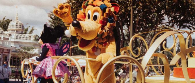 Pluto standing near the crowd in Disney world during a parade.
