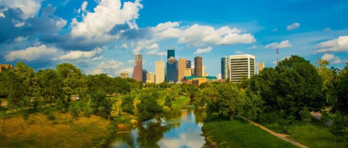 Green trees near a body of water under a blue sky during daytime in Houston, Texas, USA.