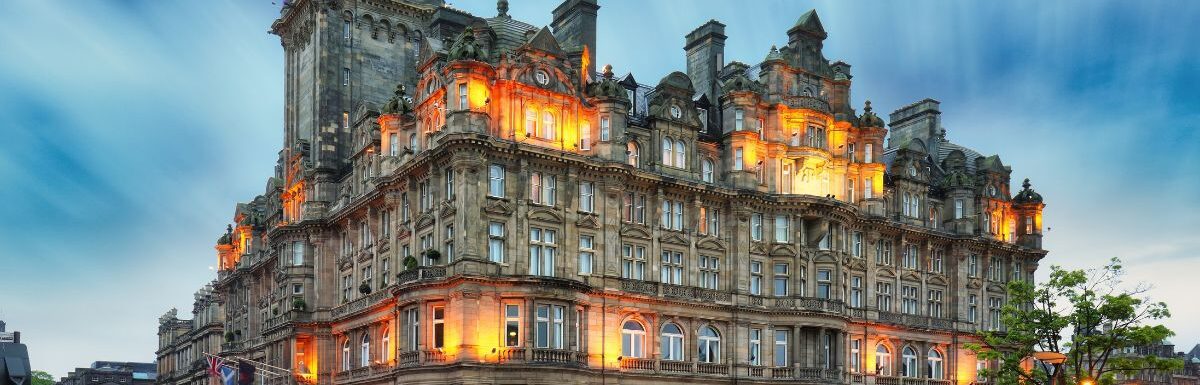 Edinburgh at night scene with Lights on Princess street and Balmoral hotel on background.