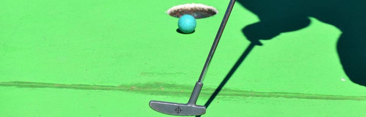 A person playing golf and the ball is about to shoot in the hole.