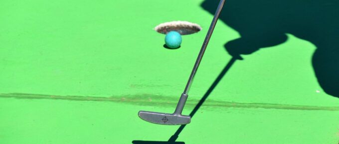 A person playing golf and the ball is about to shoot in the hole.