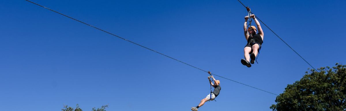 Two people on a zipline during the day.