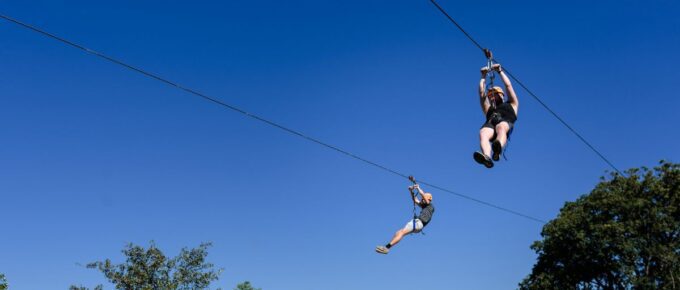Two people on a zipline during the day.