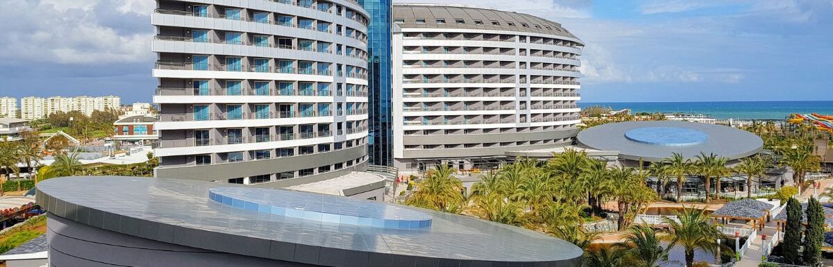 Aerial view of Royal Wings luxury five stars hotel exterior, park and inner territory, blue swimming pools, palms and chaise lounges, aquapark, tents and carousel in Turkey.