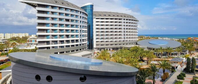 Aerial view of Royal Wings luxury five stars hotel exterior, park and inner territory, blue swimming pools, palms and chaise lounges, aquapark, tents and carousel in Turkey.