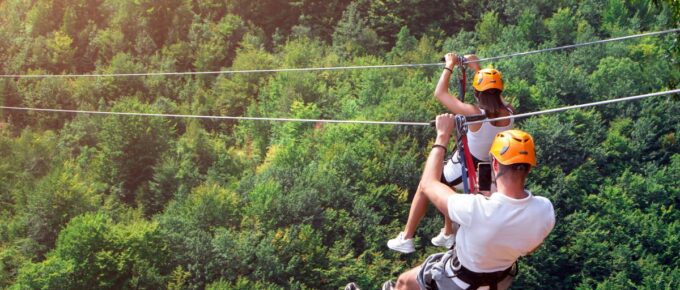 Tourists ride on the Zipline wearing white shirts and helmet.