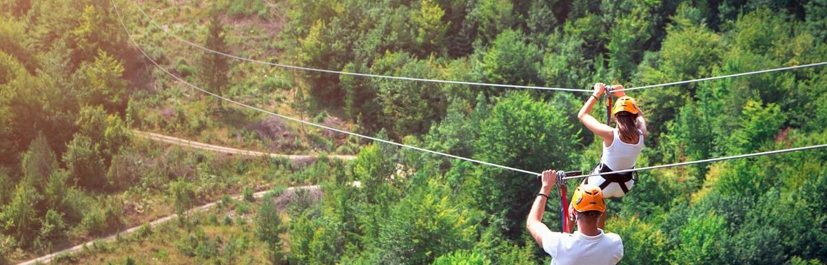 Tourists ride on the Zipline wearing white shirts and helmet.