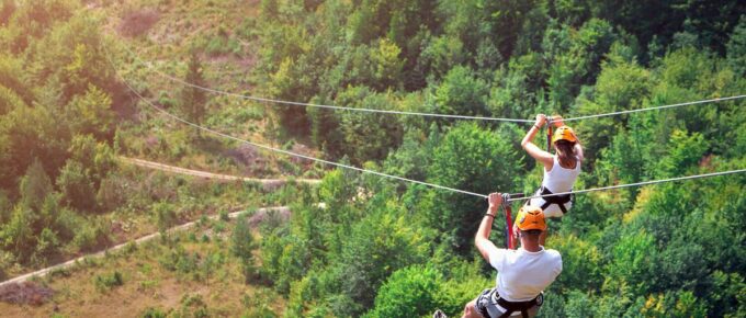 Tourists ride on the Zipline wearing white shirts and helmet.