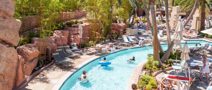 Lazy river pool in a hotel with people and trees around during the day.