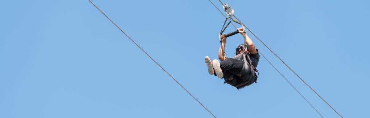 American woman against a blue sky on a zipline.