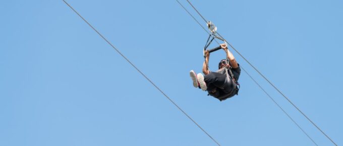 American woman against a blue sky on a zipline.